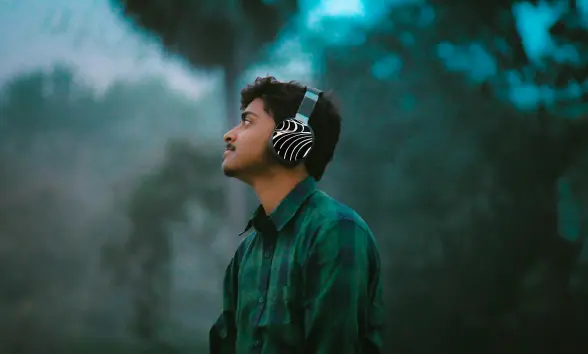 Person holding headphones with a sticker wrap in soft natural lighting